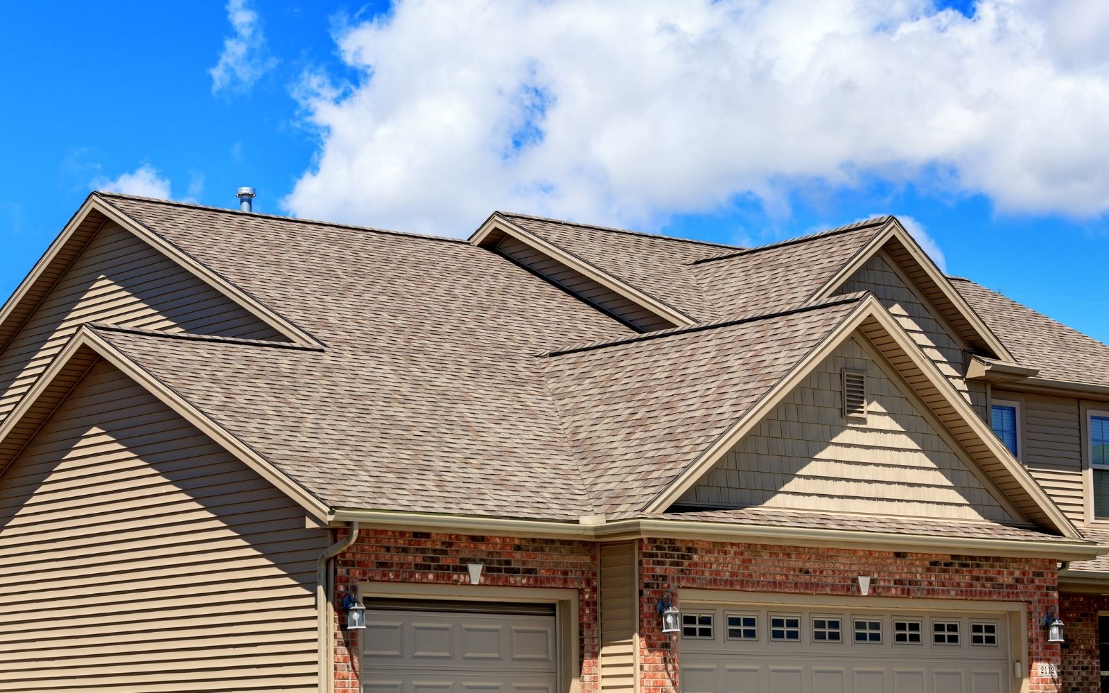 Crew installing new roof shingles on a Houston home at sunset
